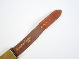 brown leather watch strap with brass buckle on a white surface