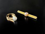 two gold rings and a pearl ring on a black surface