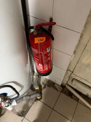 a fire extinguisor in the corner of a bathroom