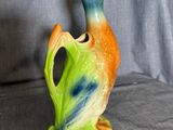 a small vase with a bird on it on a gray surface
