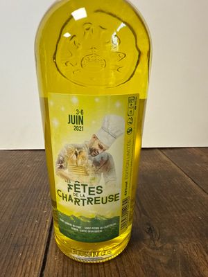 une bouteille de liquide jaune ornée d'un chat, posée sur une table en bois