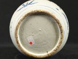 a blue and white vase with a red dot on it