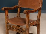 an old wooden chair with a leather seat on a carpeted floor