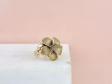 une bague en forme de fleur en or posée sur un bloc de marbre blanc