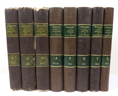 six old books are lined up in a row on a white surface