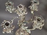 a silver candelab with five flowers on it