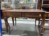 a wooden table with two drawers and a glass case behind it
