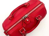a red bag with a zipper on it sitting on a white surface