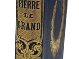 un vieux livre bleu aux bords dorés posé sur une surface blanche