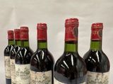 six bottles of red wine are lined up on a table