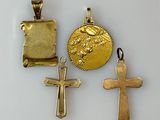 three gold crosses and a gold coin on a white surface