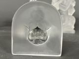 a clear glass figurine sitting next to a small figurine on a table