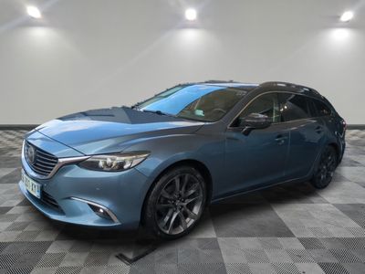 une Mazda Grand Touring break bleue garée sur un sol à damier