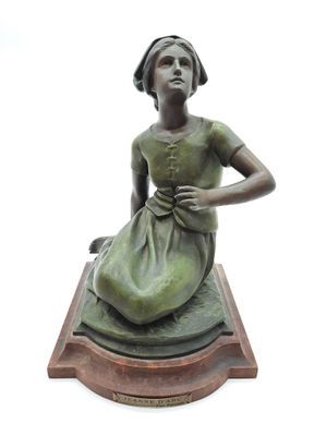 statue d'une femme en robe verte, assise sur un socle en bois