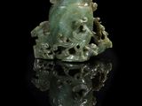 une image représentant une figurine en jade vert posée sur une surface noire