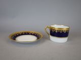 a blue and white cup and saucer with gold trim