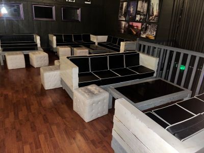 Des tables et des bancs sont alignés dans une pièce au sol en parquet.