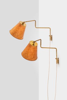 a pair of brass wall lamps on a white wall next to a white wall
