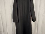 a black coat is hanging on a hanger in front of a white curtain