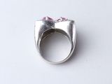 silver ring with pink stones on top of it on a white surface