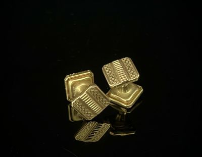une paire de boutons de manchette plaqués or sur un fond noir