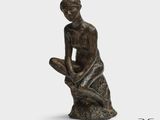 une statue représentant une femme assise sur un rocher, les mains posées sur les genoux