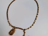 bracelet plaqué or avec des breloques et un stylo sur un fond blanc