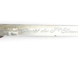 a silver knife with writing on it on a white surface