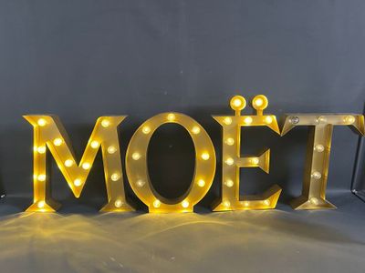 the word moet is lit up with yellow light bulbs