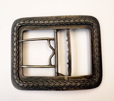 une boucle de ceinture en métal sur laquelle est fixée une boucle en métal