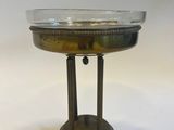 an antique brass plate with a glass bowl on a stand