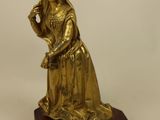 brass figurine of a woman holding a bird on a wooden base