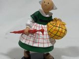 une figurine représentant une femme tenant un panier de pommes