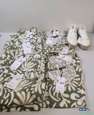 un tas de vêtements posé sur une table, à côté d'une paire de chaussures