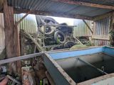 a blue boat sitting in the middle of a junkyard