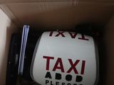 une boîte sur laquelle est apposé un panneau « taxi » et qui contient un ordinateur portable