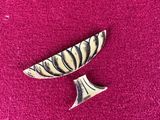 an image of a small silver object on a pink surface