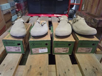 quatre paires de chaussures posées sur des cartons, sur une table
