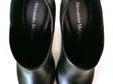 a pair of black shoes that are on a white surface