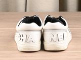 white sneakers with black soles sitting on top of a wooden table