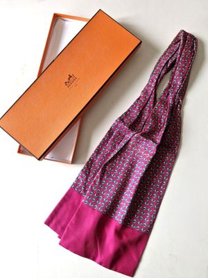 purple and pink scarf in a gift box next to a pink and orange bag