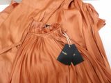 an orange dress with a tag on it sitting on a white surface