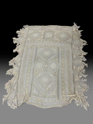un chemin de table en dentelle blanche ancienne à franges sur fond noir