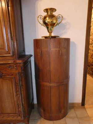 un vase posé sur un socle en bois dans une pièce