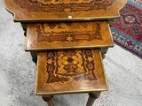 Trois tables en bois aux motifs complexes sont posées sur un tapis dans une pièce