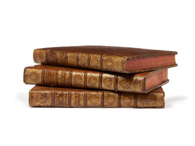 trois vieux livres empilés sur une surface blanche