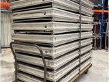 une grande pile de plateaux métalliques posée sur une palette dans un entrepôt