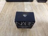 two boxes of nars cosmetics sitting on a wooden table