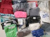 de nombreux types de vêtements différents, rangés dans des sacs posés sur la table
