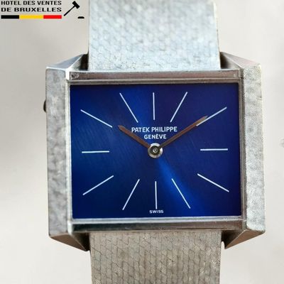 une montre en argent au cadran bleu posée sur une table